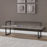 Long wooden bench with metal frame against a wall with decorative art pieces.