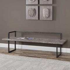 Long wooden bench with metal frame against a wall with decorative art pieces.